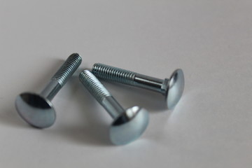 three large metal screws or bolts on a white background