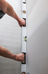 man holds metal level near wall at construction