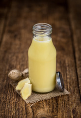 Old wooden table with fresh Ginger Juice (close-up shot; selective focus)