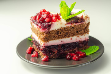 Colorful multi-layered cream chocolate cake with cherry jam and pomegranate