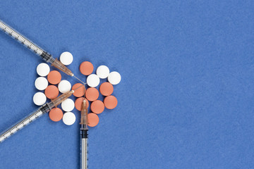 Syringe with injectable coronavirus vaccine solution on a blue background. Pills and vitamins. COVID pandemic protection. Top view. Copy space
