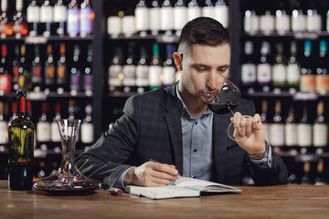 Sommeliers male tasting red wine and making notes aroma degustation card