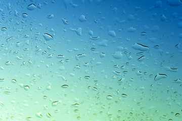 The glass of the car in the water droplets against the sky, coloured stripe.