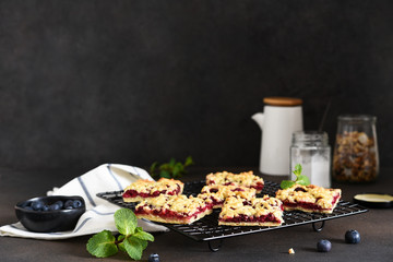 Tasty grated pie with cherries and blueberries on a dark background. Horizontal focus.