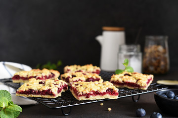 Tasty grated pie with cherries and blueberries on a dark background. Horizontal focus.