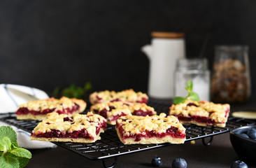 Tasty grated pie with cherries and blueberries on a dark background. Horizontal focus.