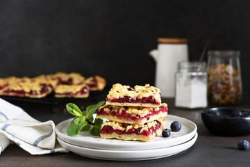 Tasty grated pie with cherries and blueberries on a dark background. Horizontal focus.