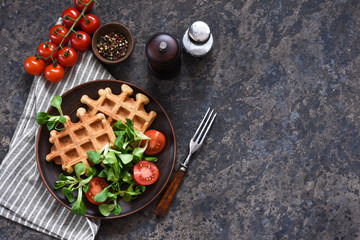 Fototapeta na wymiar Cheese waffles with corn salad and tomans - healthy breakfast on a concrete background.