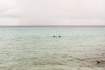 Fototapeta na wymiar Tropical sea with two snorkeling people in the distance at Curacao