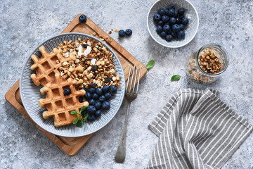 Belgian waffles with granola and blueberries for breakfast.