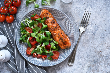 Grilled salmon slice and salad with tomatoes on the kitchen table. Menu for the restaurant.