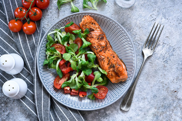 Grilled salmon slice and salad with tomatoes on the kitchen table. Menu for the restaurant.