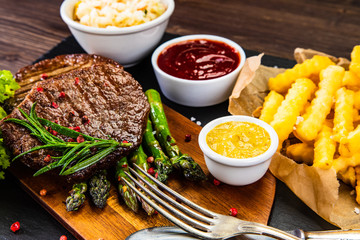 Barbecue beef steak french fries and vegetables on black stone