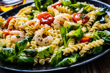 Pasta with prawns and vegetables on wooden background