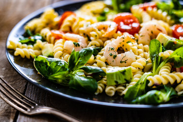 Pasta with prawns and vegetables on wooden background