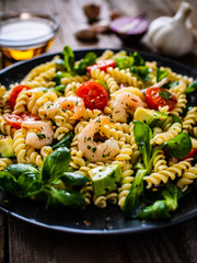 Pasta with prawns and vegetables on wooden background