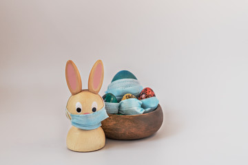 Isolated painted easter eggs and rabbit in medical masks. Easter during the coronavirus pandemic. Safety comes first during Easter 2020:the concept of self-isolation and quarantine during the Covid-19