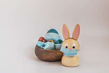 Isolated painted easter eggs and rabbit in medical masks. Easter during the coronavirus pandemic. Safety comes first during Easter 2020:the concept of self-isolation and quarantine during the Covid-19