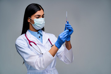 Girl doctor with a phonendoscope on her neck in blue medical gloves with a syringe in her hands. Medical concept