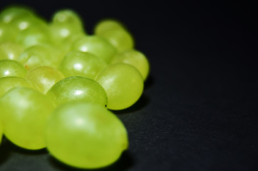 green grape berries on a black background with copy space