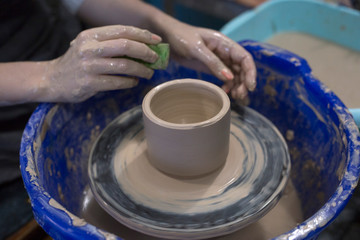 Fototapeta na wymiar Woman's hands use sponge to remove excess water in clay cup. Master class in pottery ceramics