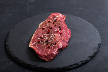 Raw fresh marbled meat and seasonings on dark background top view