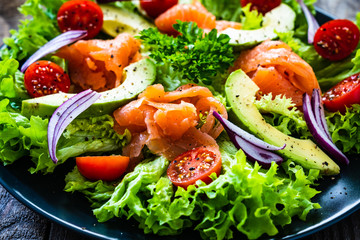 Salmon salad - smoked salmon and vegetables on wooden background