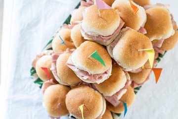 Italian party panini piled in stack in finger food style. Small panini sandwich with ham and salami. Italian food birthday party with flag. Happy food italian catering banquet with prosciutto