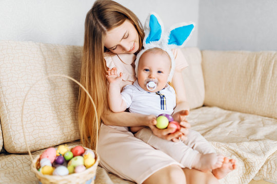 Happy Easter. A mother and baby, with rabbit ears on Easter day, with Easter painted eggs, have fun, play and cuddle