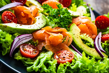Salmon salad - smoked salmon and vegetables on wooden background