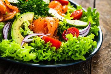 Salmon salad - smoked salmon and vegetables on wooden background