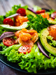 Salmon salad - smoked salmon and vegetables on wooden background