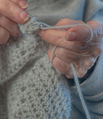Hands doing the age old art or craft with thread called crochetting.