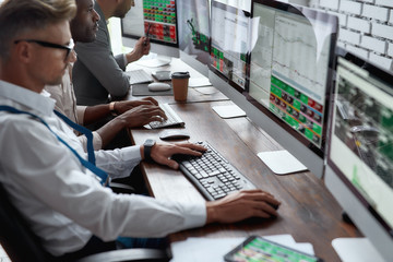 Think about it. Achieve it. Three businessmen sitting at desktop front PC computers with financial...