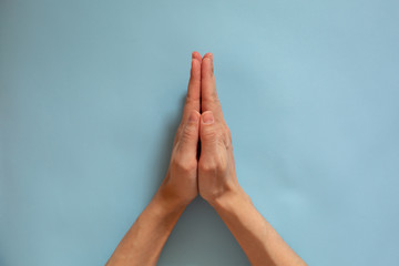 A gesture of supplication, a request for help. Female hands on a blue background.