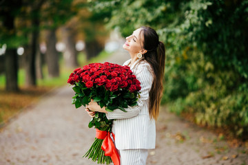 Valentine's Day 101 Birthday Gift For You. Beautiful woman with stylish makeup. Girl holding a gorgeous big bouquet of roses. Perfect sensual lips. Fashion Makeup. Woman in earrings