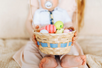 Happy Easter. Close-up of a happy mother and small children's hands holding colored eggs in a basket