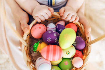 Happy Easter. Close-up of a happy mother and small children's hands holding colored eggs in a basket