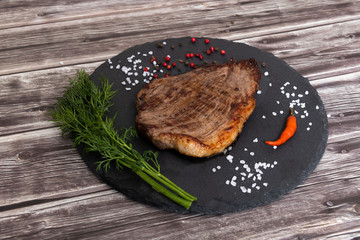 Grilled beef steak ribeye with salt and pepper on dark wooden background top view