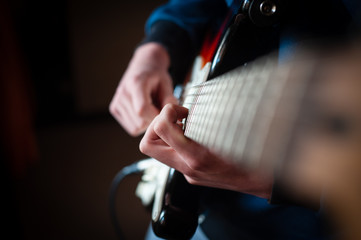 Male hands playing electric solo guitar with closeup photo. Learning musical instrument, music shop or school, blues bar or rock cafe, having fun enjoying hobby concept