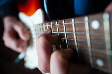 Fototapeta premium Male hands playing electric solo guitar with closeup photo. Learning musical instrument, music shop or school, blues bar or rock cafe, having fun enjoying hobby concept