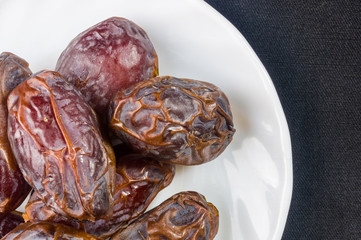 Big luxury dried date fruit in bowls on the dark surface, kurma ramadan kareem concept, close up.
