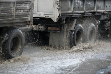 Car motion through big puddle of water splashes from the wheels on the street road. Water splash...