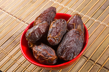 Big luxury dried date fruit in bowls on the bamboo mat, kurma ramadan kareem concept, close up.