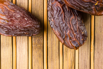 Big luxury dried date fruit in bowls on the bamboo mat, kurma ramadan kareem concept, close up.