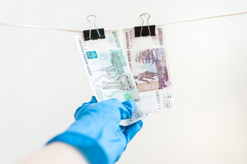 A hand in a blue rubber glove withdraws money from a clothes dryer.