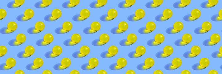 Round yellow pills on blue background. Seamless pattern. Horizontal banner, site header. Vitamin, beauty supplement.