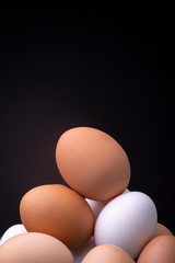 Studio still life even lit close up of a stack of light brown and white chicken eggs in detail and showing texture of eggshell.
