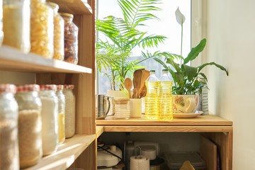 Kitchen utensils, sunflower oil on wooden table in pantry, food storage at home
