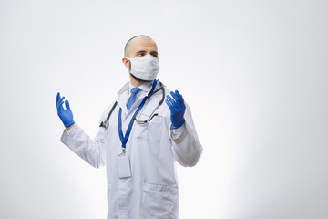 A caucasian doctor in a protective face mask to avoid the spread coronavirus (COVID-19) with hands in disposable medical gloves. A bald physician with a beard preparing to do a procedure.
